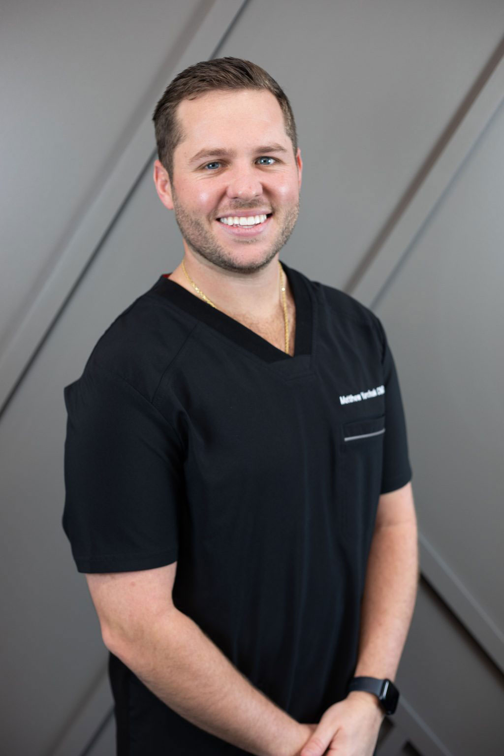 The image features a man wearing scrubs and a stethoscope, standing against a wall with a professional background, likely a portrait for a medical professional s website.