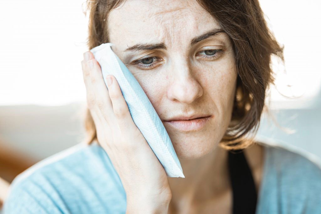 A woman with a cloth on her nose, possibly indicating she has a cold or flu, expressing concern or discomfort.