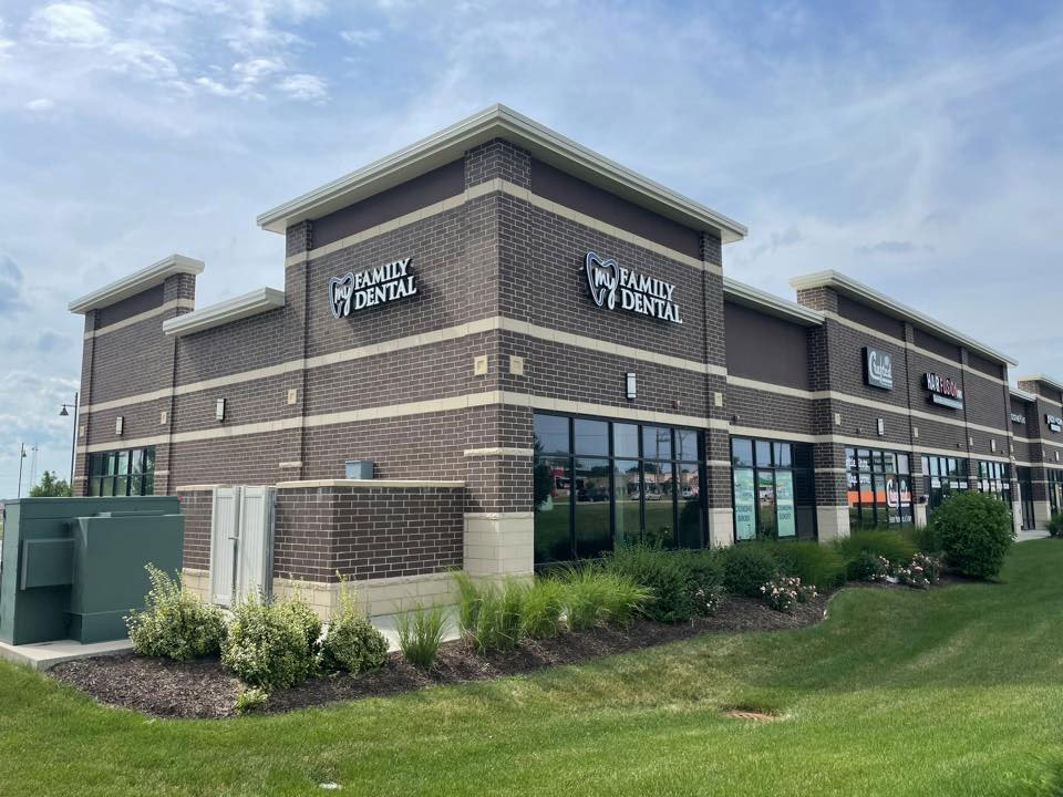 The image displays a commercial building with a sign indicating  Family Dental  on the facade, situated in a suburban setting with a clear sky above.