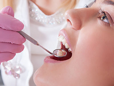 The image shows a dental professional performing a procedure on a patient s teeth using dental instruments and tools.