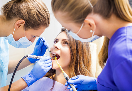 The image shows dental professionals performing oral care on a patient in a clinical setting.