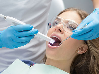 A woman receiving dental treatment with a dentist using a digital device to show her teeth on a screen.