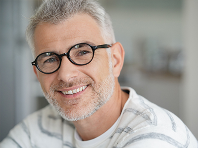 A man with a beard and glasses, smiling at the camera.